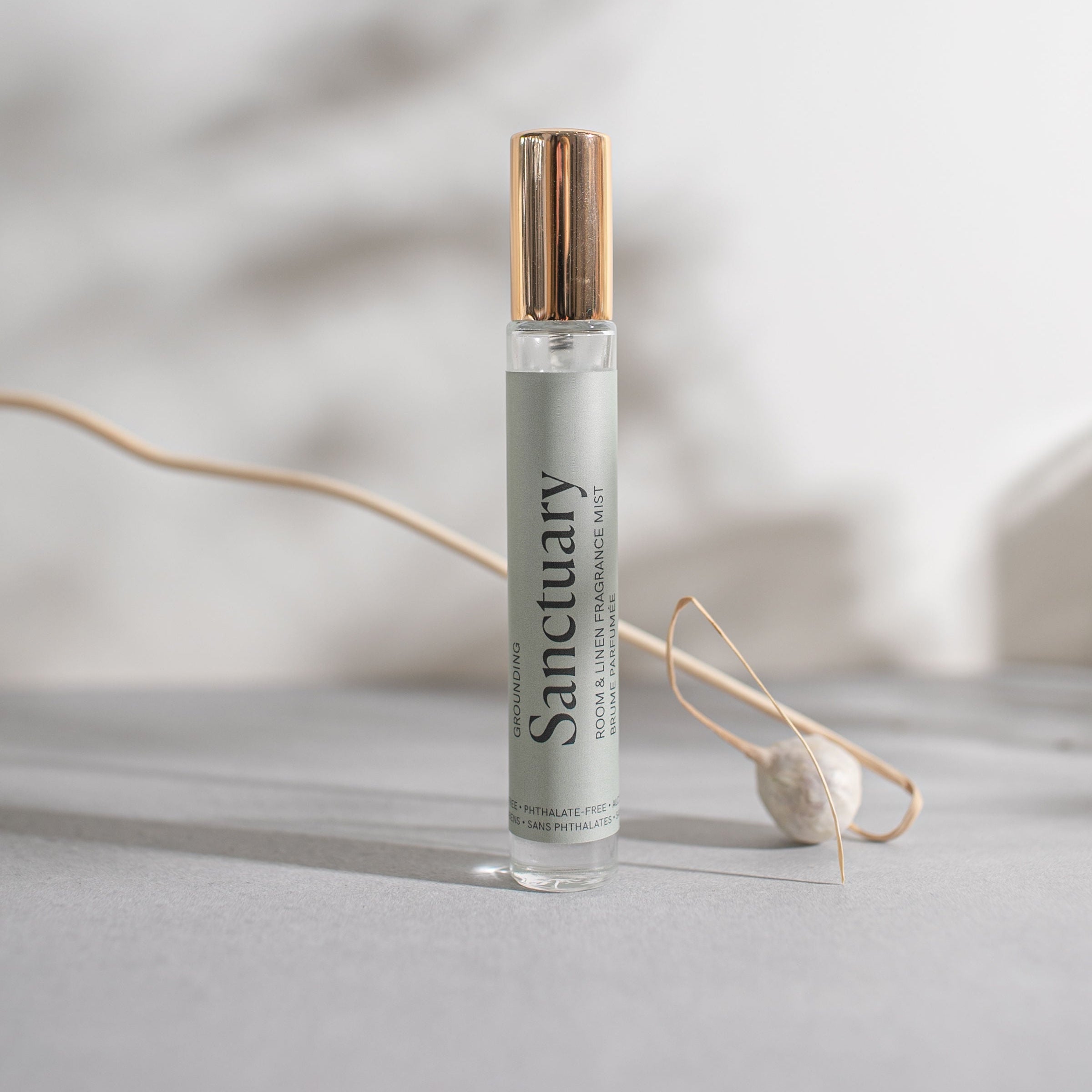 Small glass spray bottle with a gold cap, labelled 'Sanctuary' on a light background