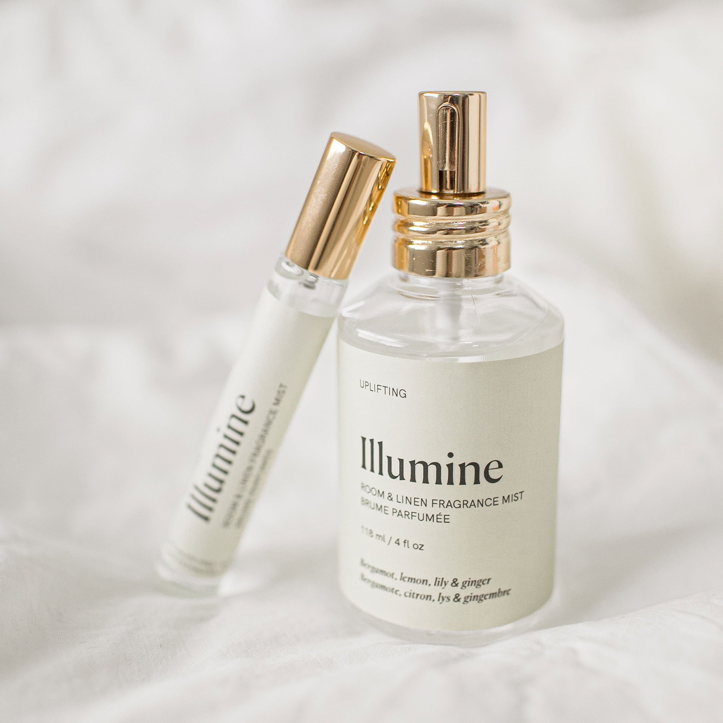 Two bottles of Illumine fragrance mist on a soft white background