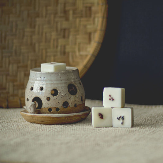 Ceramic lantern with white candles on a textured surface